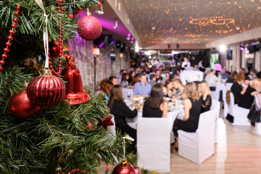 Close up of decorated christmas tree in the restaurant. New Year's corporate event of a large company. Blurred background, selective focus.