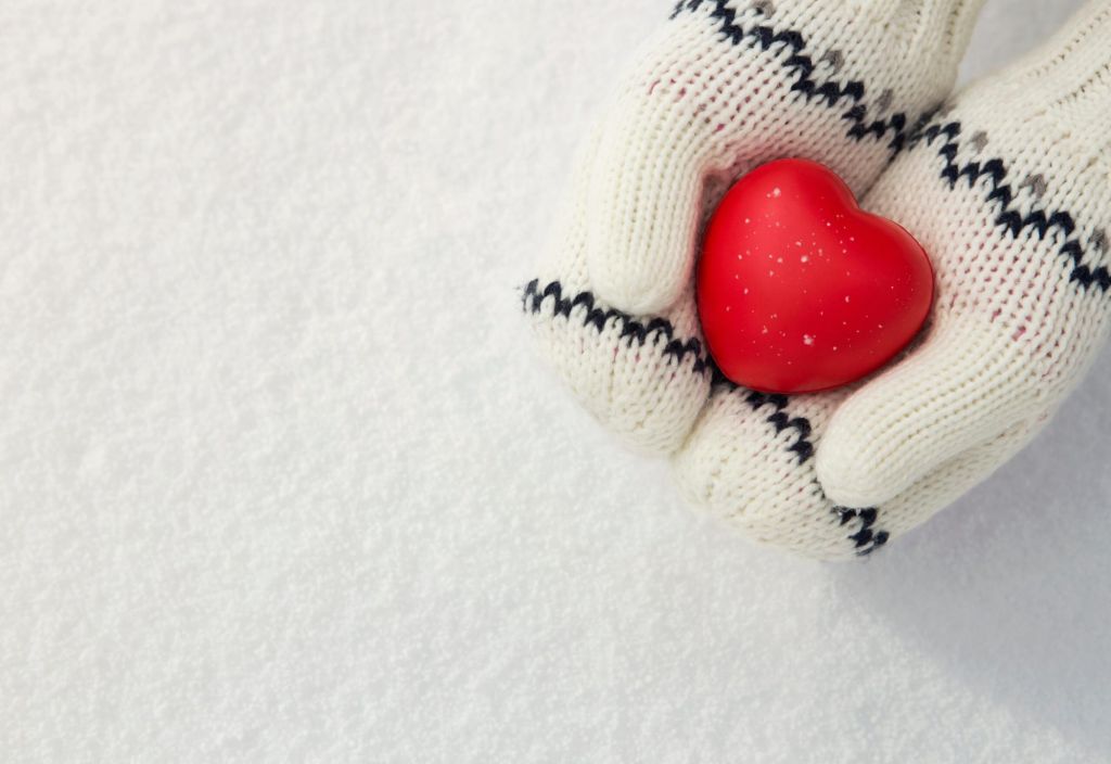 Winter background, close up of little girls hands holding red rubber heart with copy space