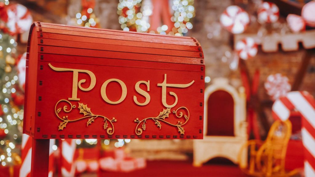 Closeup Red post box for letters to Lapland to Santa Claus. Christmas tradition. Decorative mailbox Santa Claus workshop, wrapped gifts presents boxes on holiday eve in night on xmas background